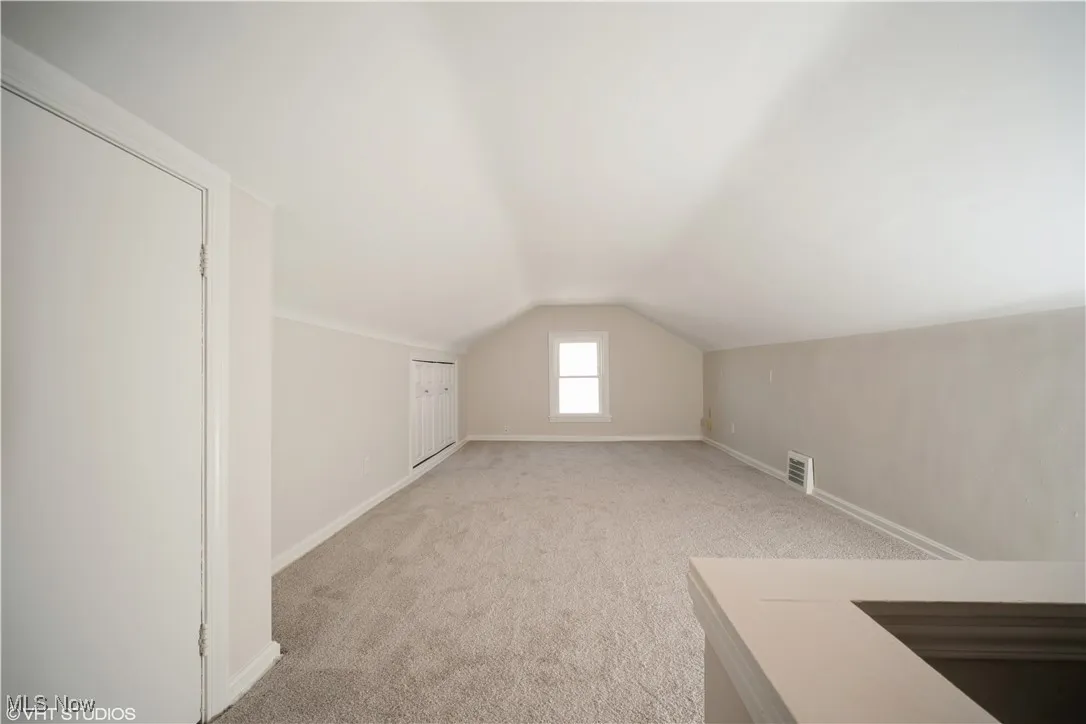 Additional living space featuring visible vents, baseboards, light colored carpet, and lofted ceiling