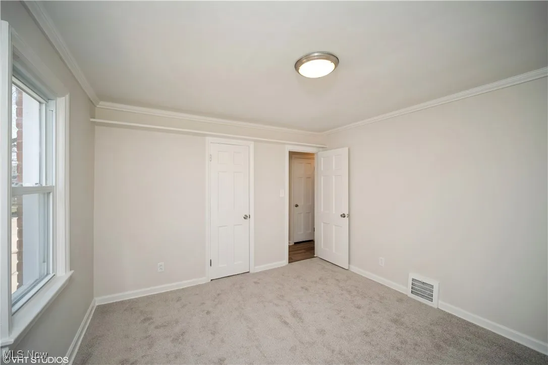 Unfurnished bedroom featuring baseboards, ornamental molding, visible vents, and carpet floors