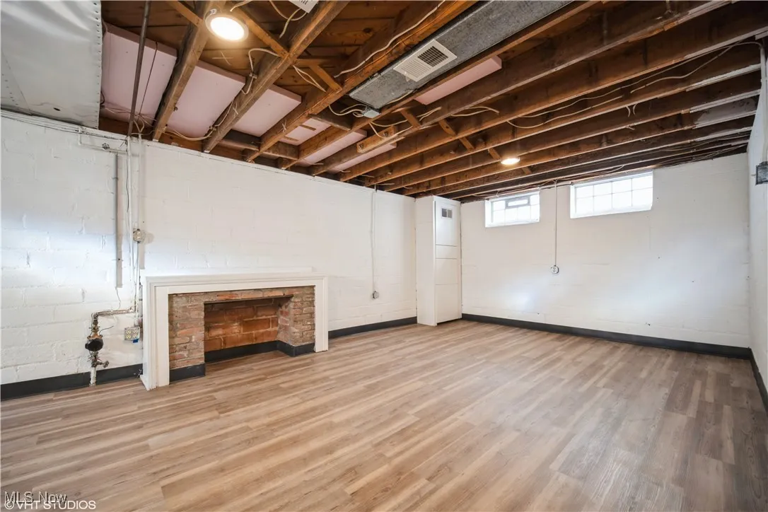 Below grade area featuring visible vents, concrete block wall, and wood finished floors
