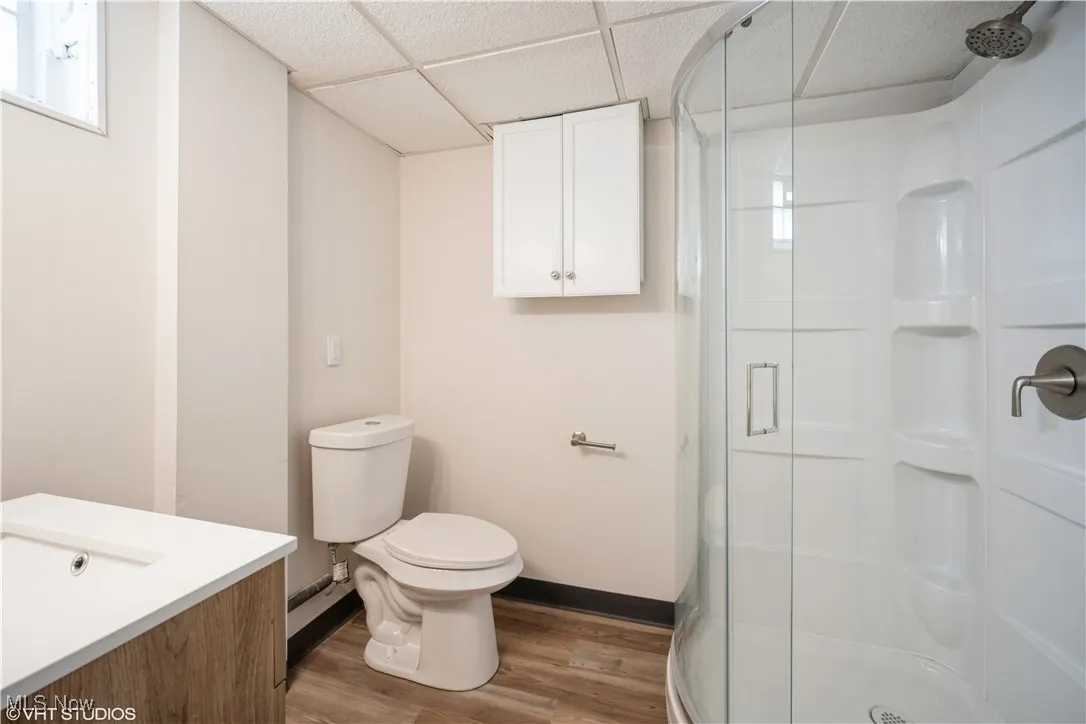 Full bath featuring a shower stall, wood finished floors, and toilet