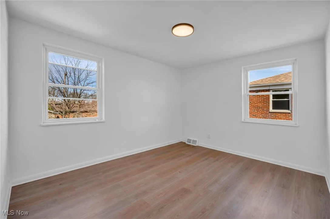 Empty room featuring visible vents, baseboards, and light wood-type flooring