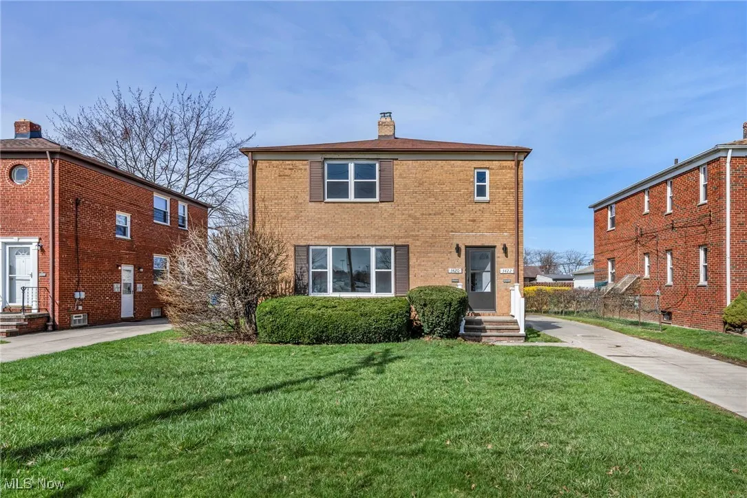 Traditional home with a chimney, driveway, a front lawn, and brick siding