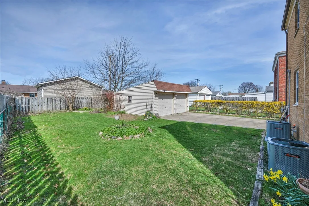 View of yard with an outbuilding, fence, a garage, and central air condition unit