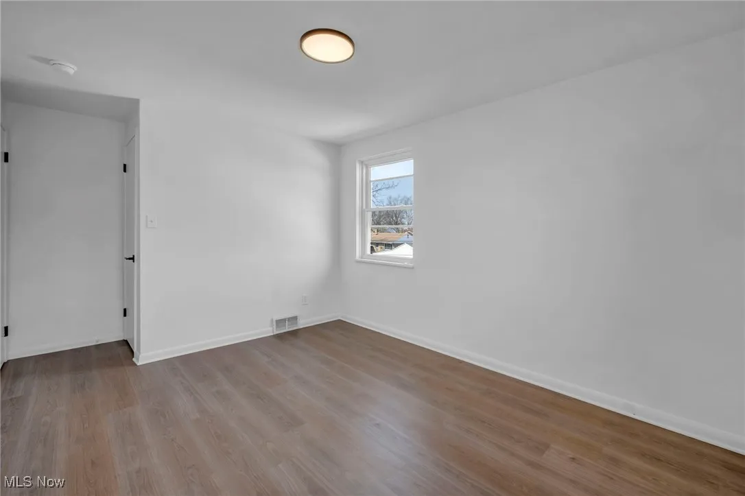 Unfurnished room with visible vents, baseboards, and wood finished floors