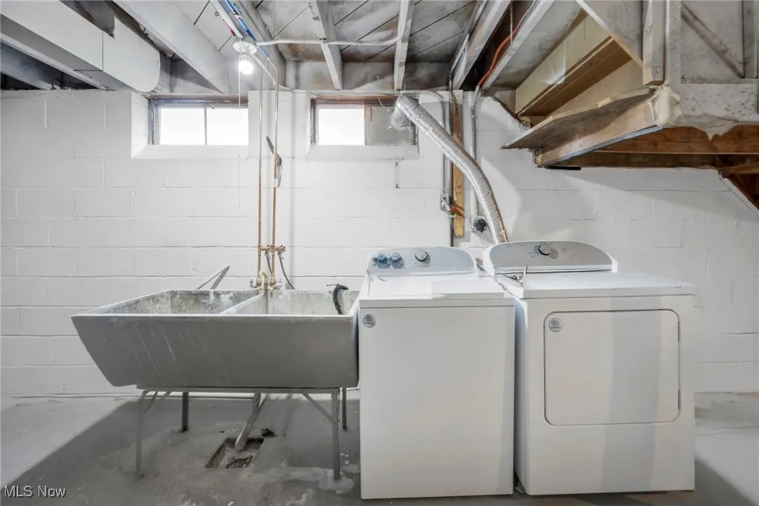 Washroom with laundry area, washing machine and clothes dryer, and a sink