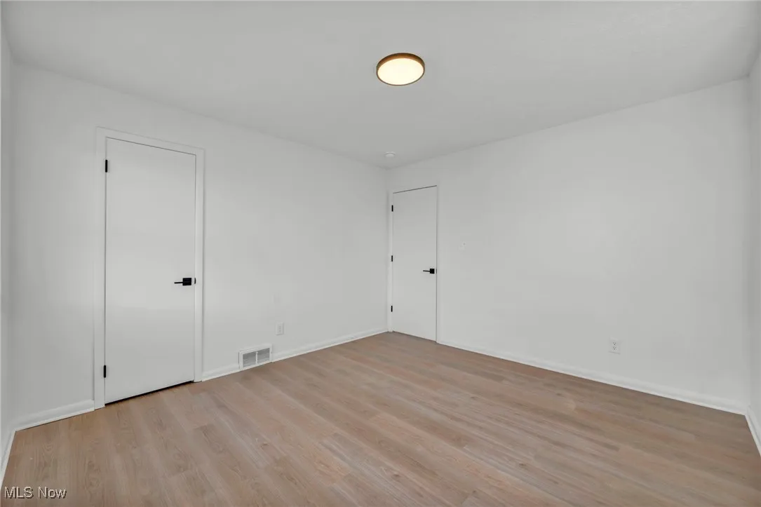 Spare room with light wood-style flooring, baseboards, and visible vents