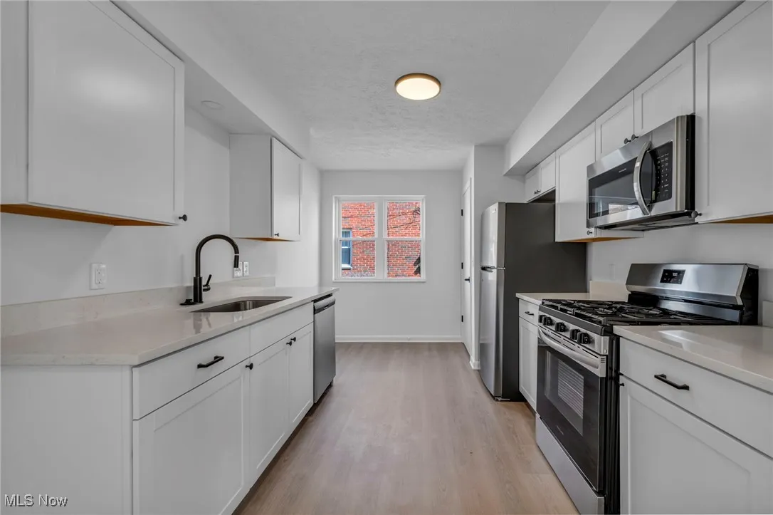 Kitchen featuring white cabinets, light countertops, a sink, and appliances with stainless steel finishes