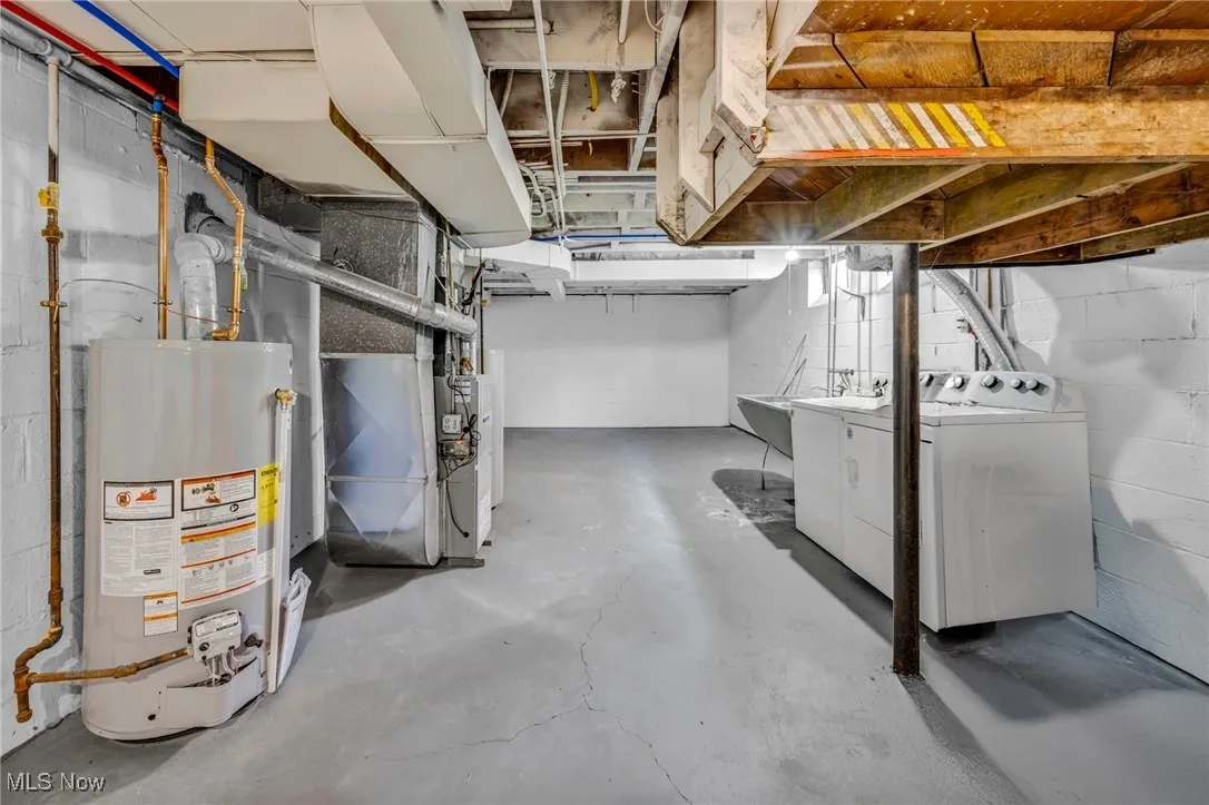 Unfinished below grade area with washer and dryer, heating unit, and water heater
