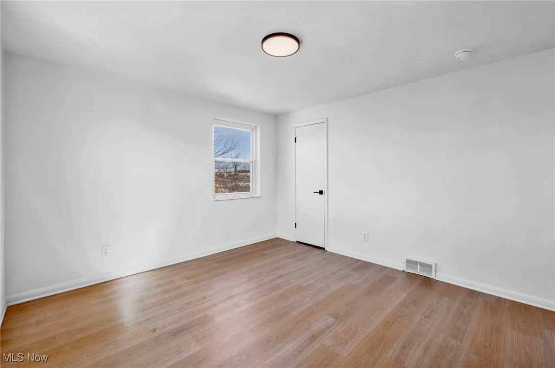 Spare room with wood finished floors, baseboards, and visible vents