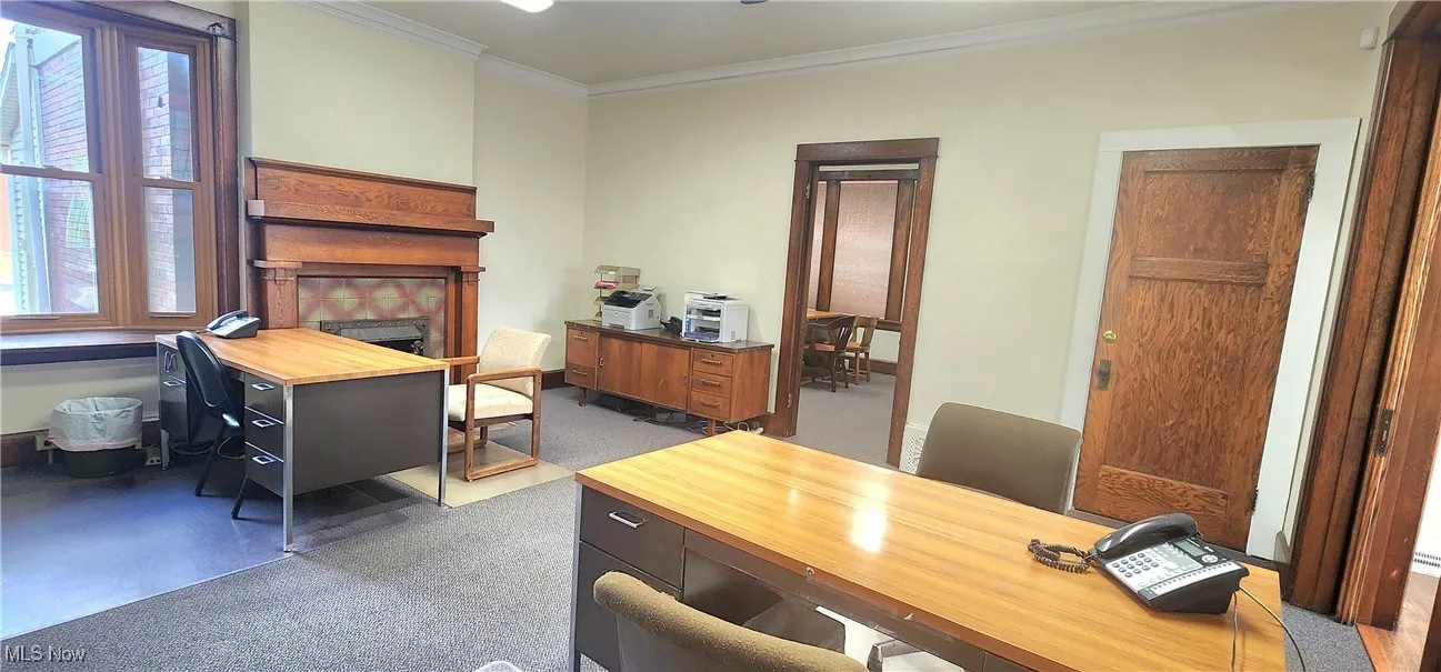 Office area with dark carpet, ornamental molding, and a fireplace