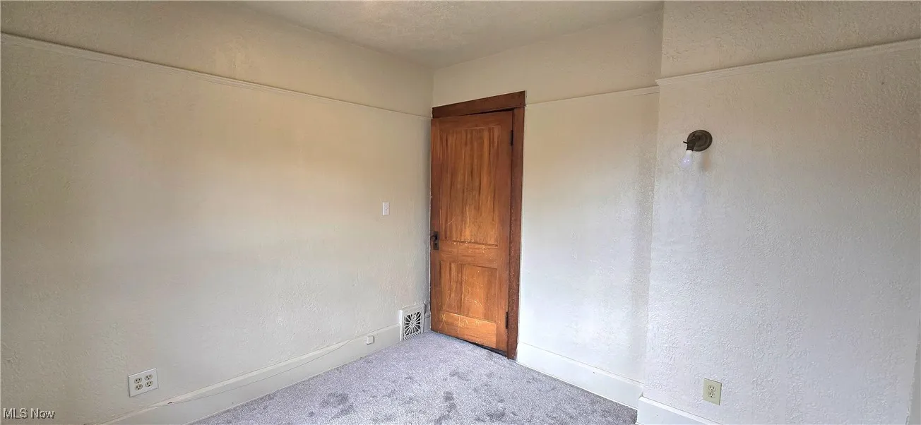 Empty room with baseboards, carpet flooring, and a textured wall