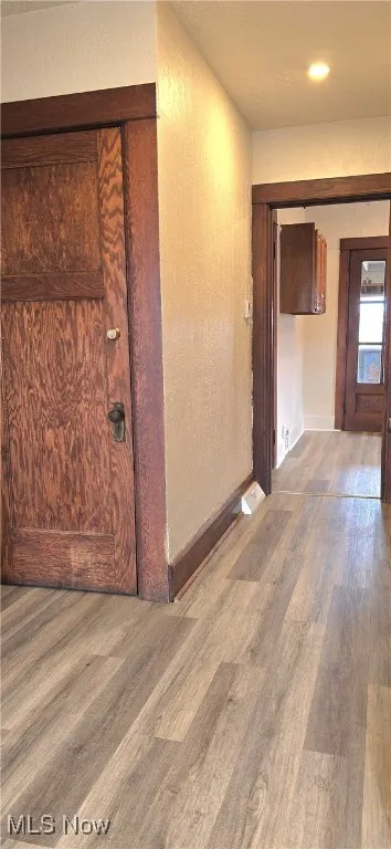 Corridor with a textured wall and wood finished floors