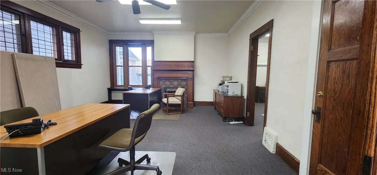 Office with dark carpet, ornamental molding, and ceiling fan