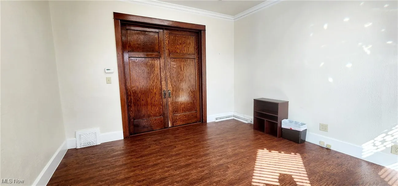 Unfurnished bedroom with ornamental molding and dark hardwood / wood-style floors