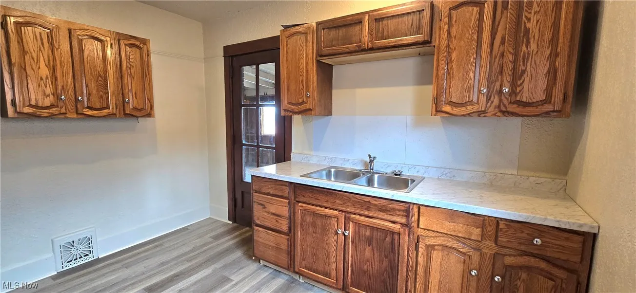 Kitchen featuring baseboards, light wood-style flooring, light countertops, visible vents, and a sink