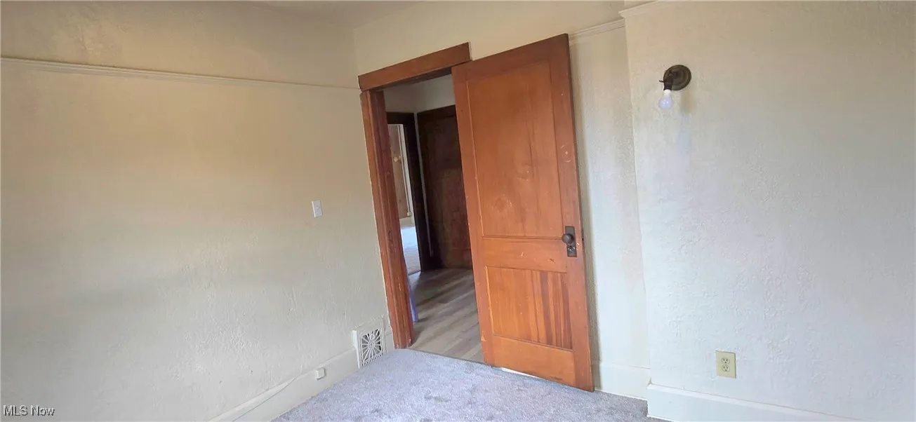 Spare room featuring light carpet, a textured wall, and visible vents