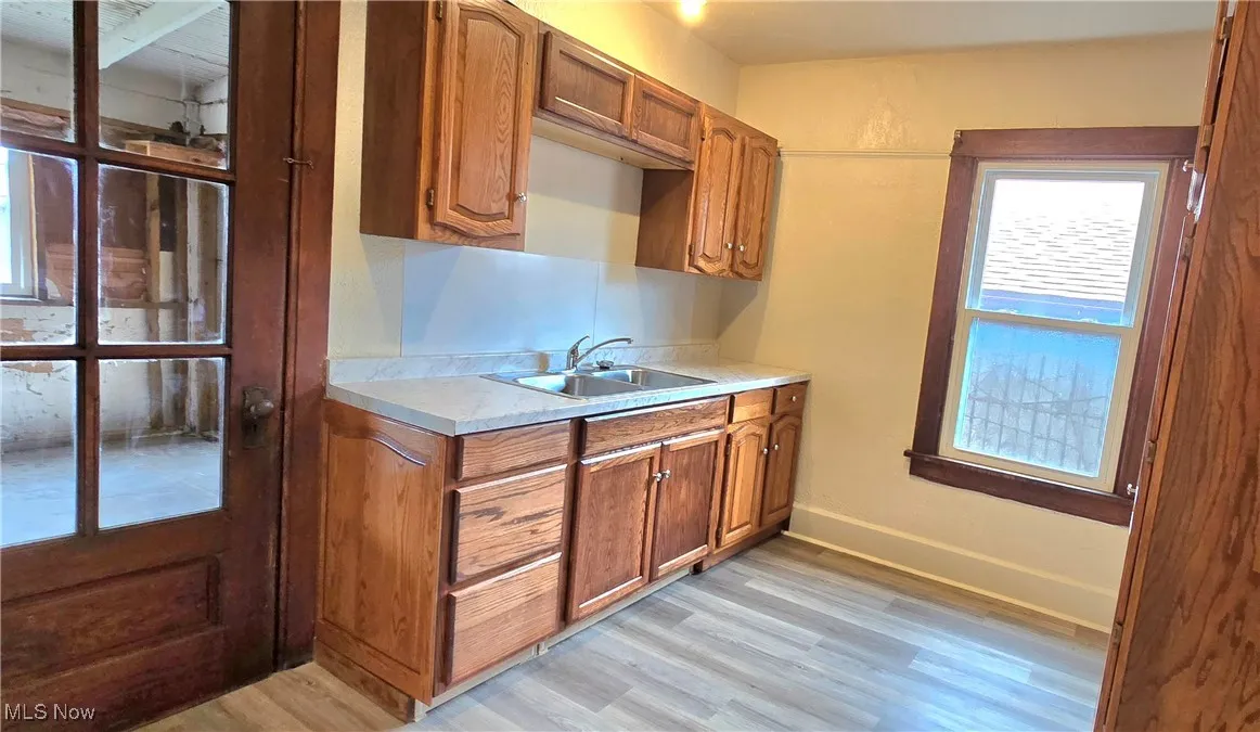Kitchen with a sink, brown cabinetry, light countertops, and light wood-style flooring
