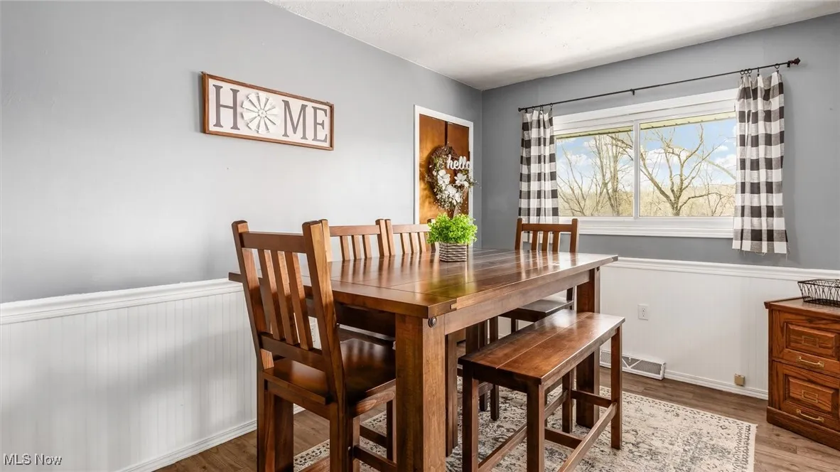Dining area with wood finished floors, wainscoting, and visible vents