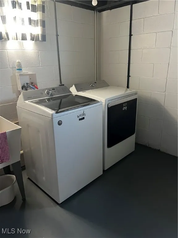 Laundry room featuring washing machine and dryer, laundry area, and concrete block wall