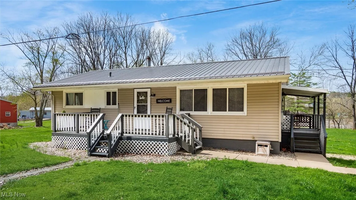 View of front of home featuring metal roof, a front lawn, and covered porch