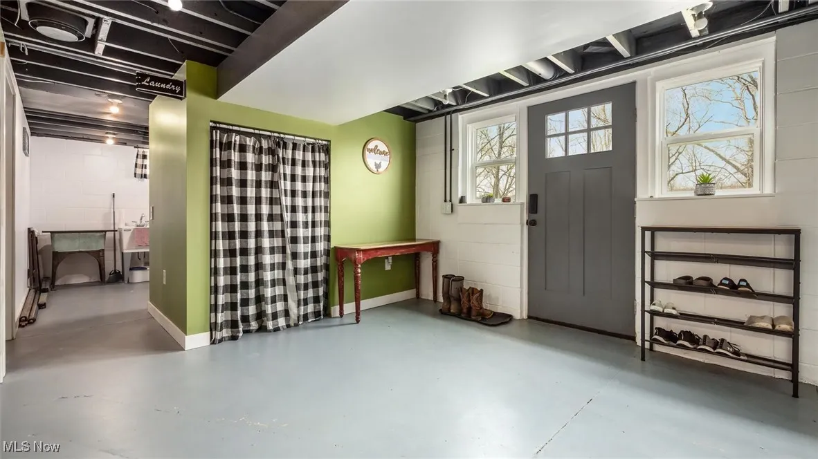 Foyer entrance featuring baseboards, concrete block wall, and finished concrete flooring
