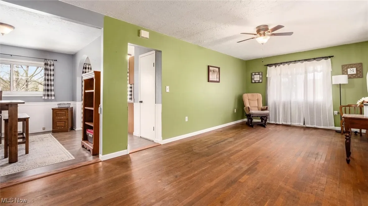 Sitting room featuring wood-type flooring, a textured ceiling, baseboards, and ceiling fan