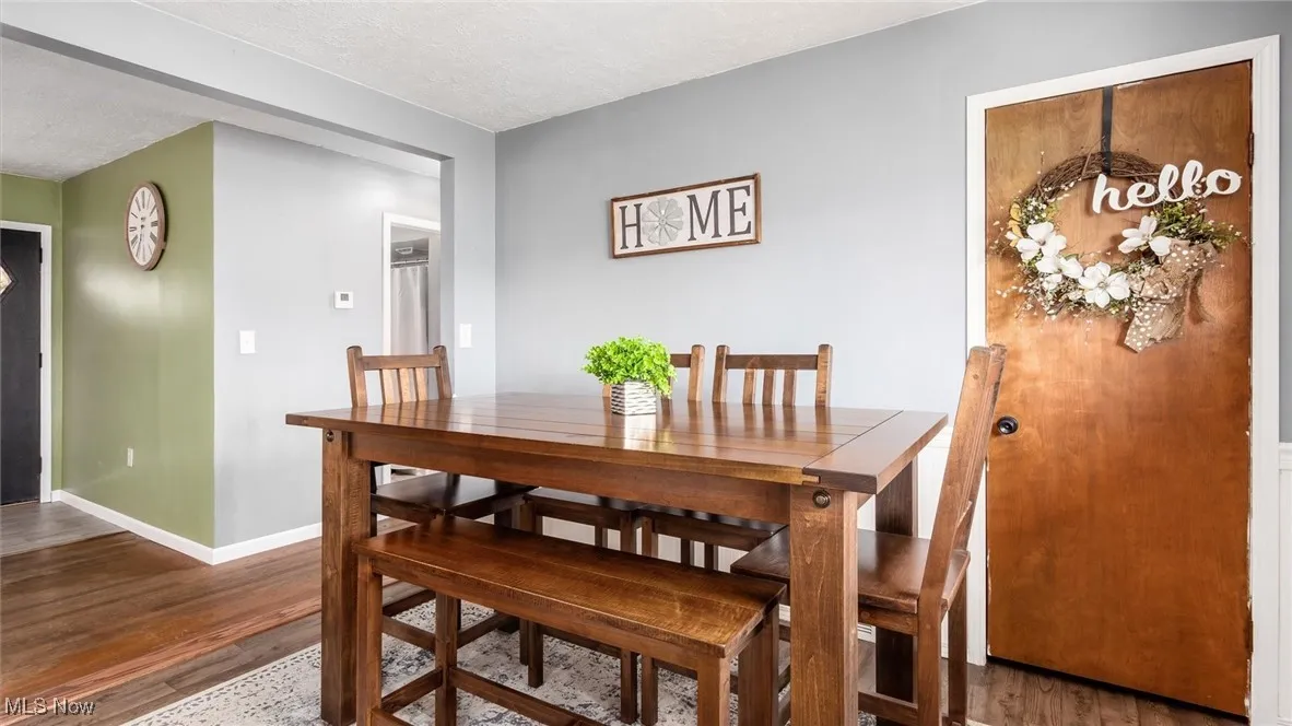 Dining room featuring baseboards, a textured ceiling, and wood finished floors