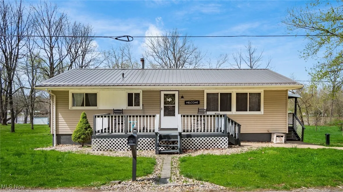 View of front of property featuring covered porch, a front yard, and metal roof