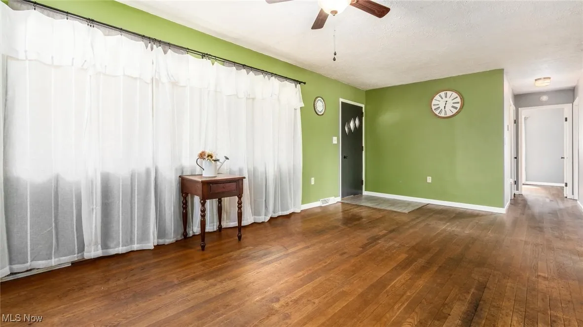 Spare room with ceiling fan, a textured ceiling, visible vents, baseboards, and hardwood / wood-style flooring