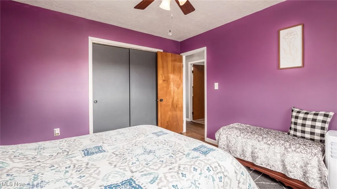 Bedroom with ceiling fan, a textured ceiling, a closet, wood finished floors, and baseboards