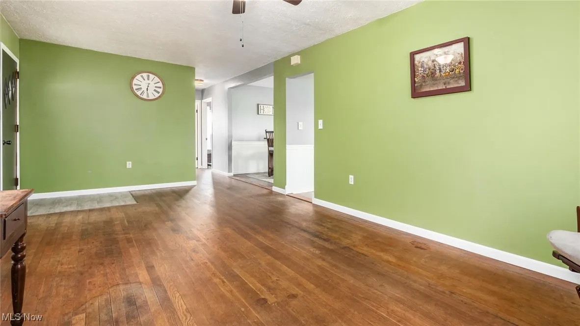 Unfurnished room featuring ceiling fan, hardwood / wood-style floors, baseboards, and a textured ceiling
