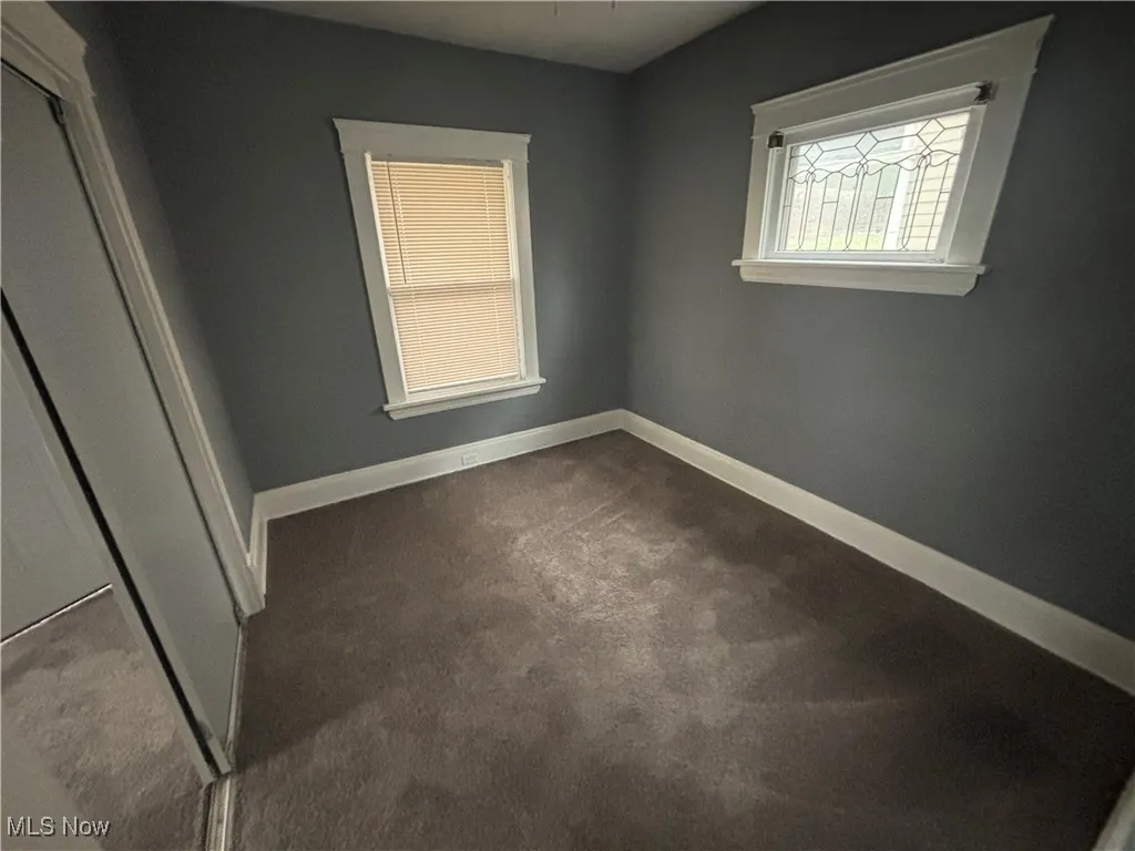 Unfurnished bedroom featuring dark colored carpet and baseboards