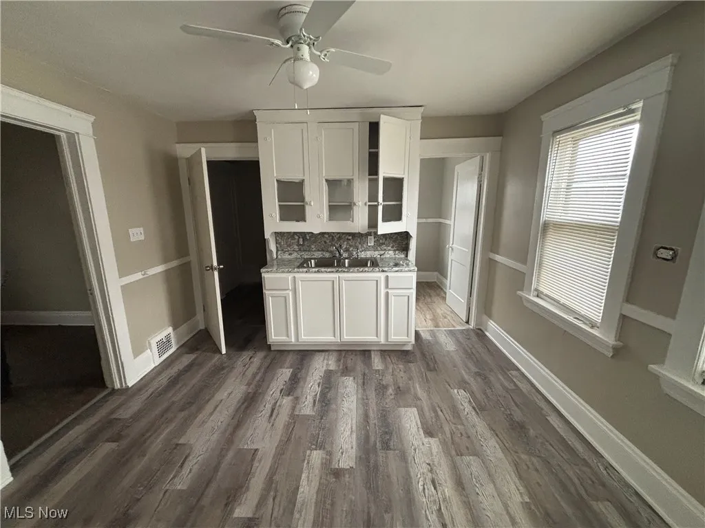 Kitchen with visible vents, a sink, dark wood-style flooring, ceiling fan, and white cabinetry