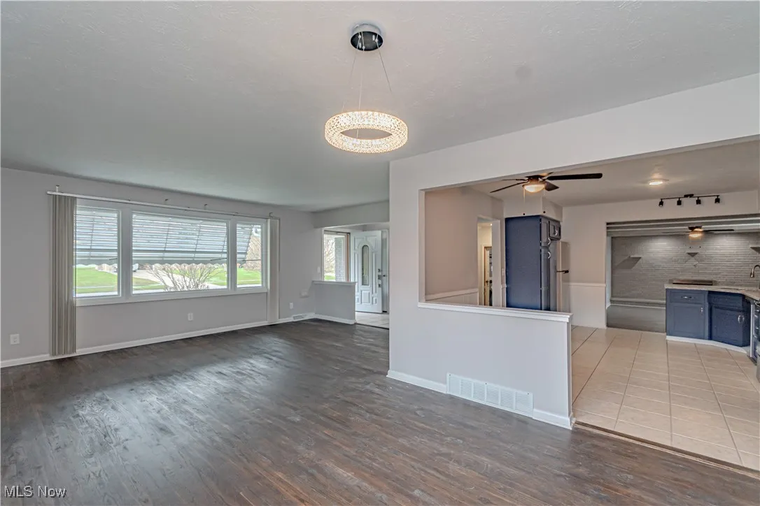 Unfurnished living room with visible vents, ceiling fan, wood finished floors, and baseboards
