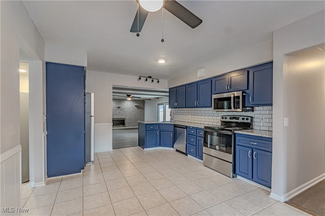 Kitchen with tasteful backsplash, a ceiling fan, blue cabinets, and stainless steel appliances