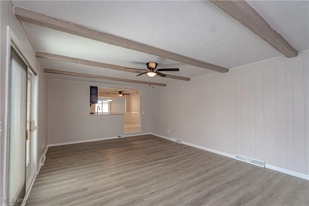 Spare room with beamed ceiling, ceiling fan, visible vents, light wood finished floors, and baseboards