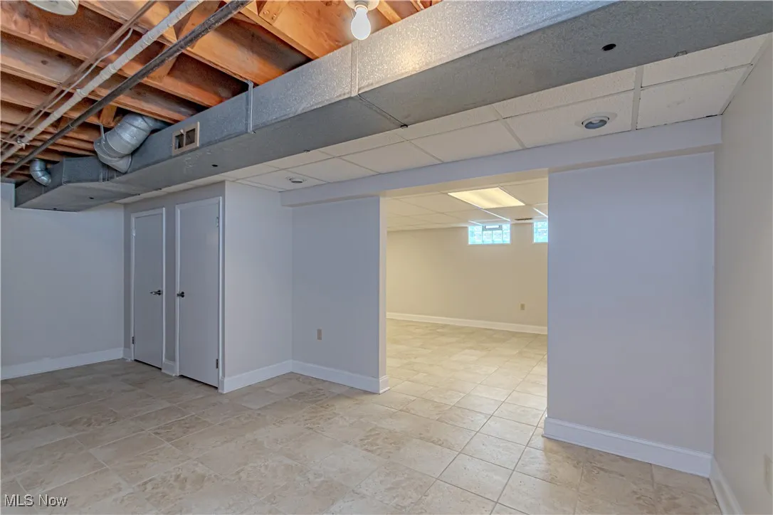 Basement with visible vents, baseboards, and a drop ceiling