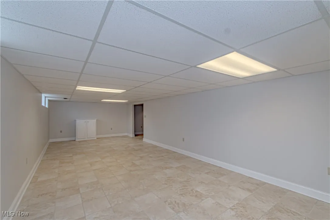 Finished basement with baseboards and a drop ceiling