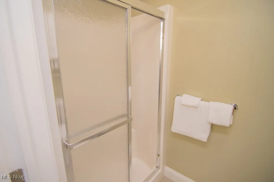 Full bathroom featuring baseboards and a shower stall