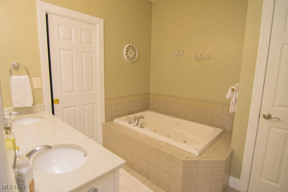 Bathroom featuring a sink, double vanity, and a jetted tub