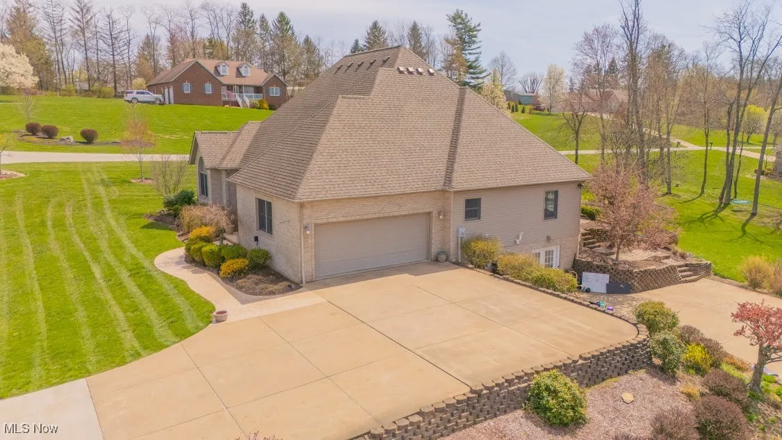 View of home's exterior with a yard, roof with shingles, brick siding, an attached garage, and concrete driveway
