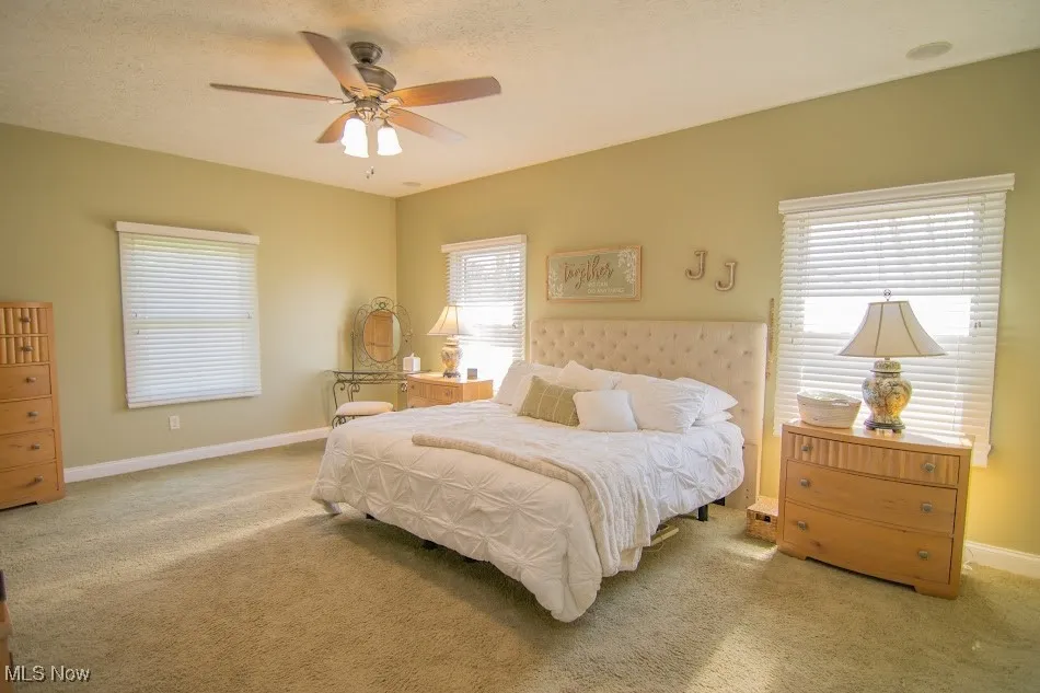 Carpeted bedroom featuring baseboards, a textured ceiling, and a ceiling fan