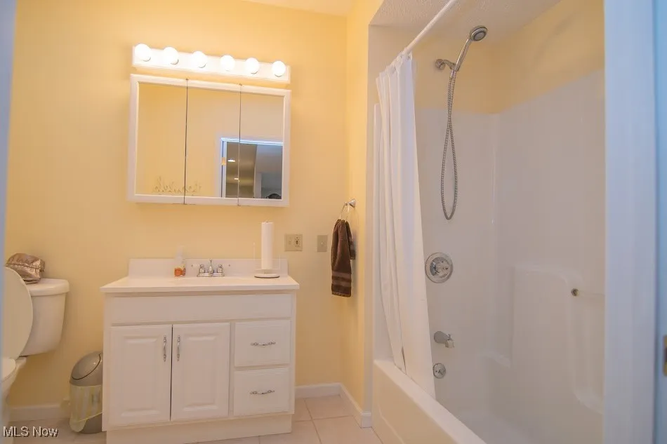 Bathroom with vanity, baseboards, tile patterned flooring, shower / tub combo with curtain, and toilet