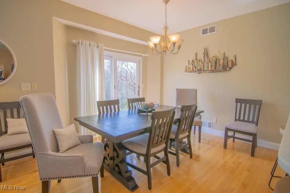 Dining area featuring a chandelier, light wood-type flooring, baseboards, and visible vents