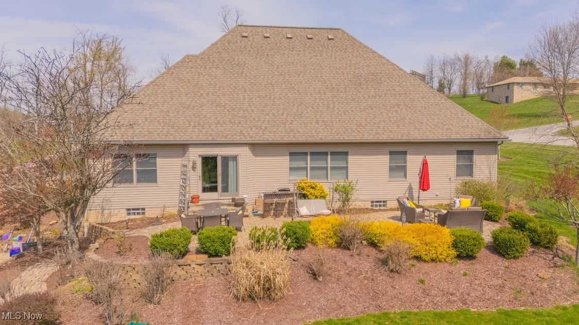 Back of house featuring a patio area, an outdoor living space, and a shingled roof
