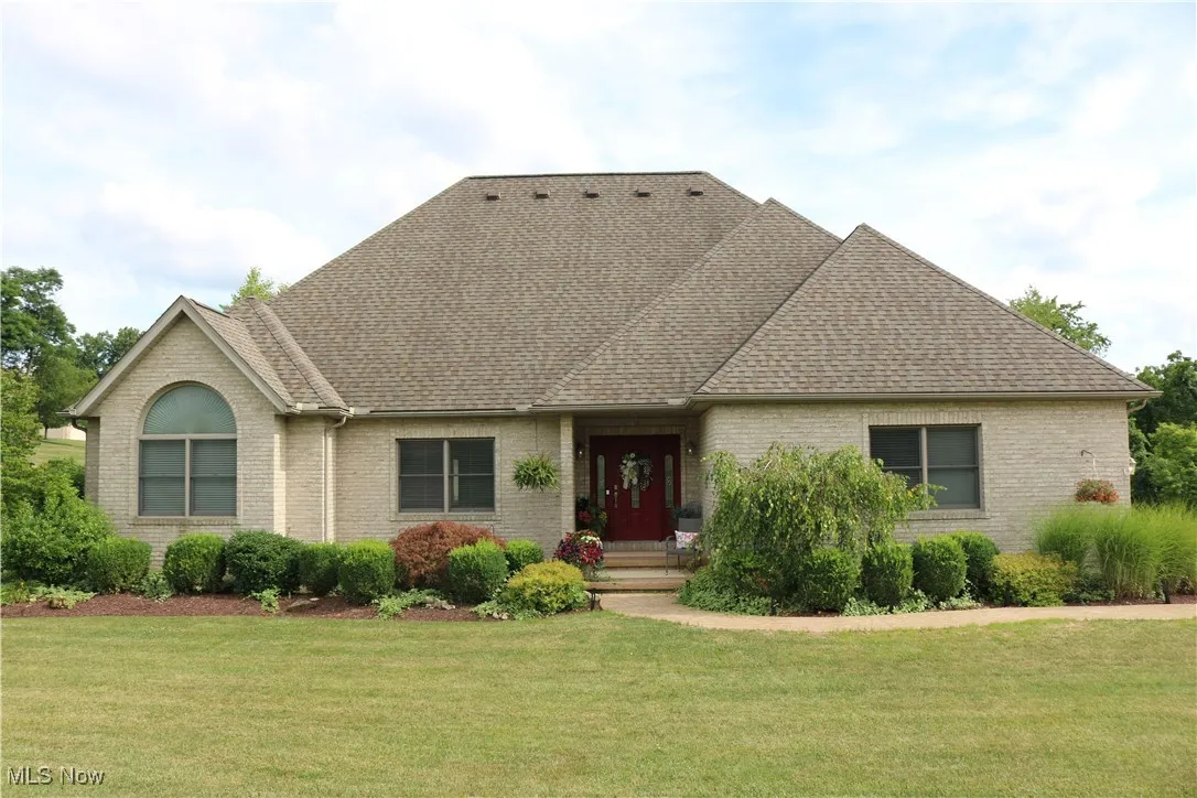 View of front of house with a shingled roof, brick siding, and a front lawn