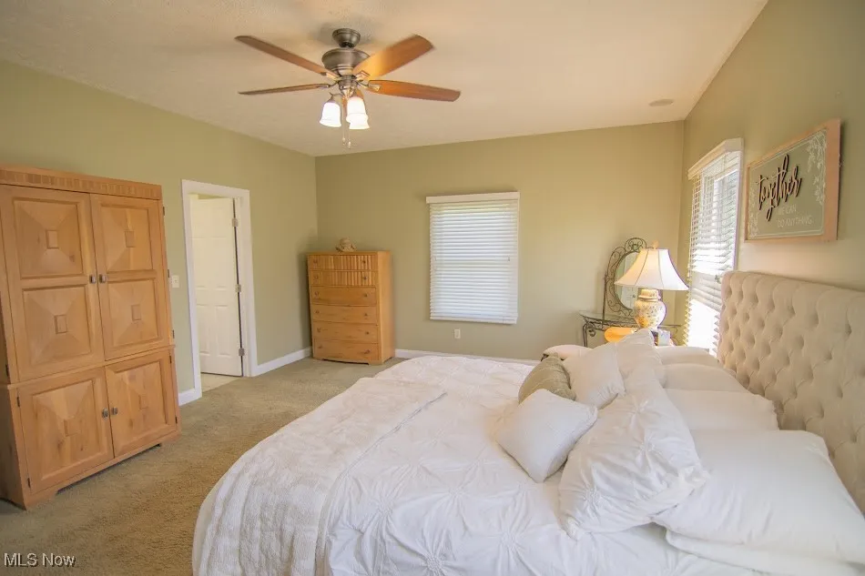 Bedroom with baseboards, a ceiling fan, and light colored carpet