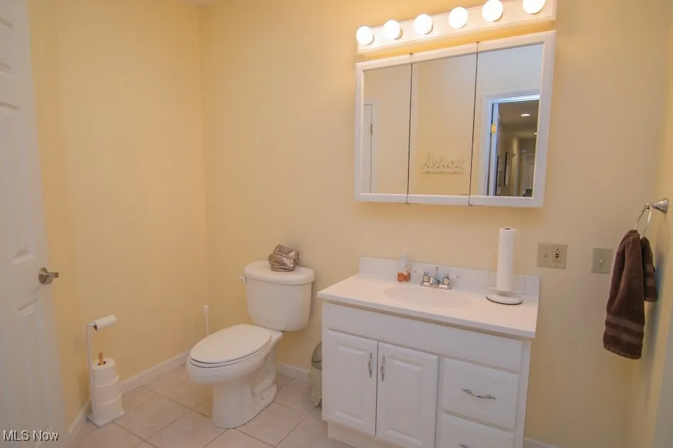 Bathroom with tile patterned floors, vanity, baseboards, and toilet
