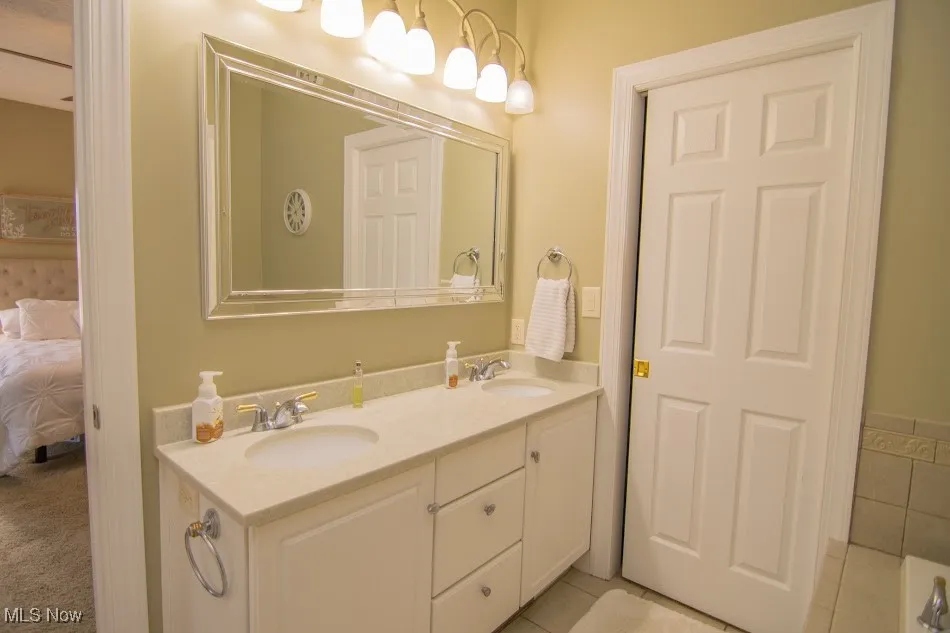 Full bathroom featuring a sink, tile patterned flooring, double vanity, and ensuite bath