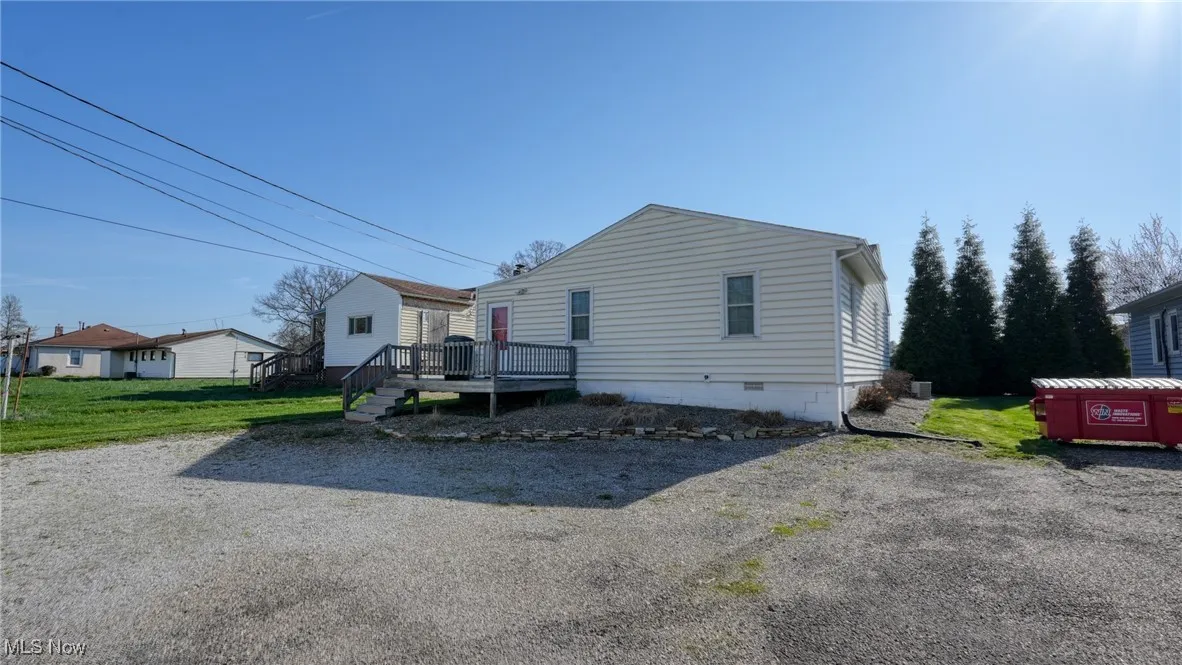 View of back of property featuring a front lawn, a wooden deck, and crawl space